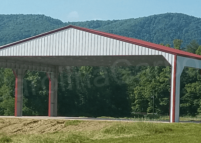 a large white metal carport with the smoky mountains visible behind them